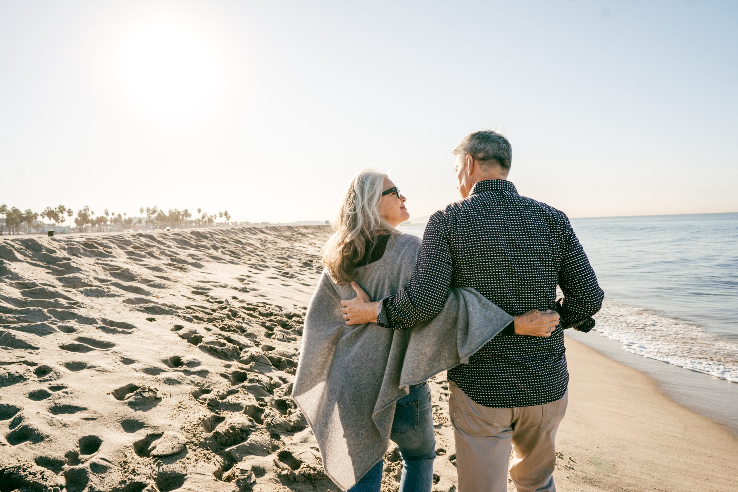 An older couple walking together along the shoreline